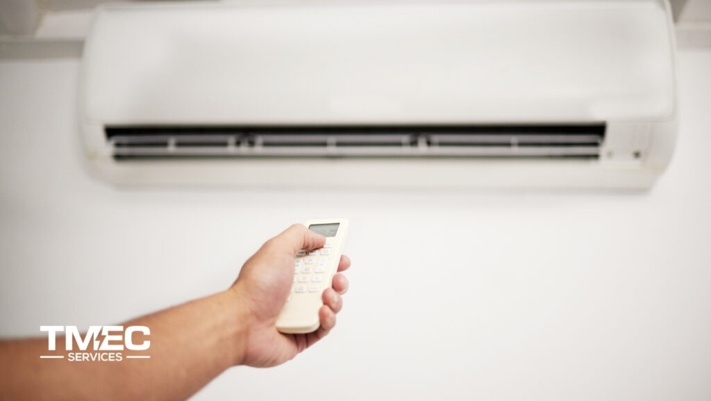 Hand holding remote control to turn on split system unit for air conditioner repair Sunshine Coast